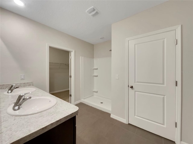 bathroom with a shower, tile patterned flooring, and vanity