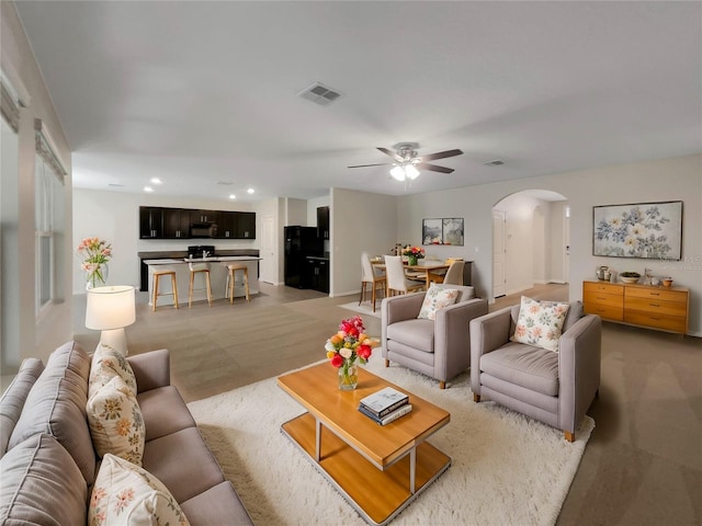 carpeted living room with ceiling fan