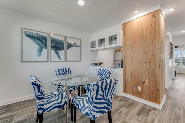 dining space featuring hardwood / wood-style floors, crown molding, and a textured ceiling