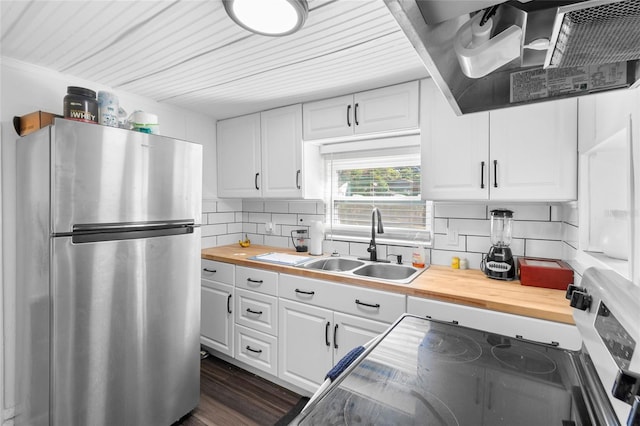 kitchen featuring wood counters, white cabinetry, stainless steel refrigerator, and sink