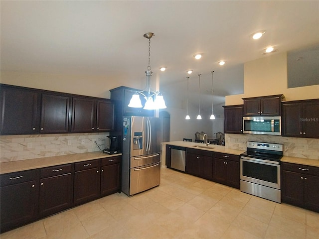 kitchen featuring hanging light fixtures, stainless steel appliances, light countertops, and a sink