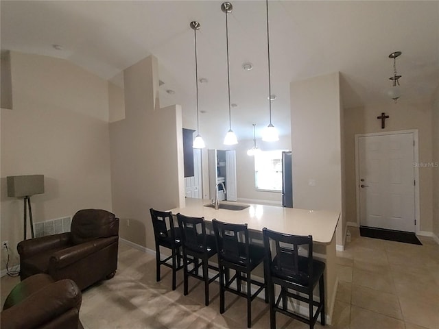 kitchen featuring light countertops, light tile patterned floors, a kitchen breakfast bar, freestanding refrigerator, and a sink