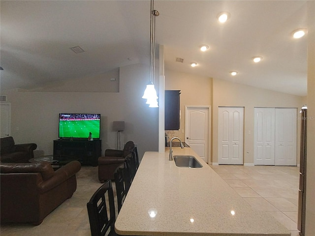 kitchen featuring a sink, visible vents, light stone counters, and vaulted ceiling