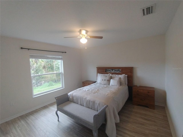 bedroom with visible vents, baseboards, and wood finished floors