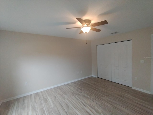 unfurnished bedroom featuring a ceiling fan, visible vents, baseboards, light wood-style flooring, and a closet