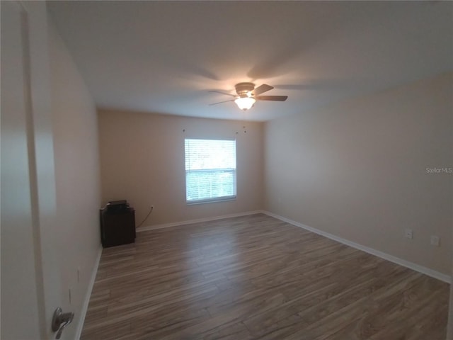 unfurnished room with baseboards, wood finished floors, and a ceiling fan