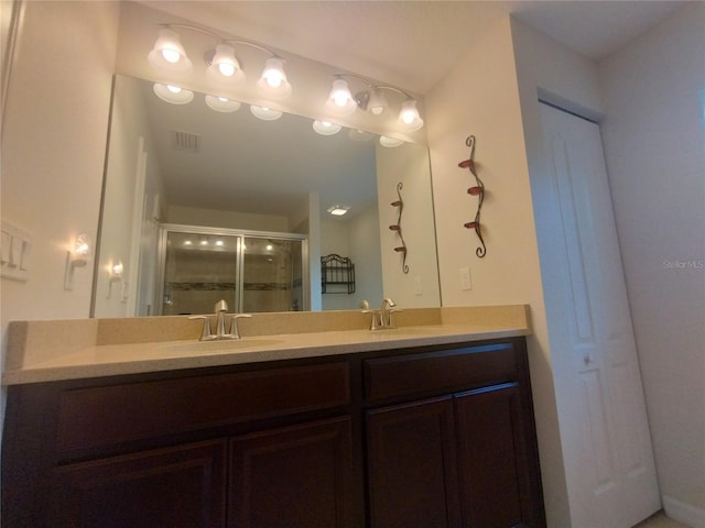 bathroom featuring double vanity, visible vents, a stall shower, and a sink