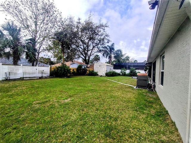 view of yard with an outbuilding, a storage unit, and a fenced backyard