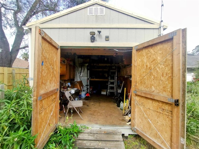 view of outbuilding with a garage, an outdoor structure, and fence