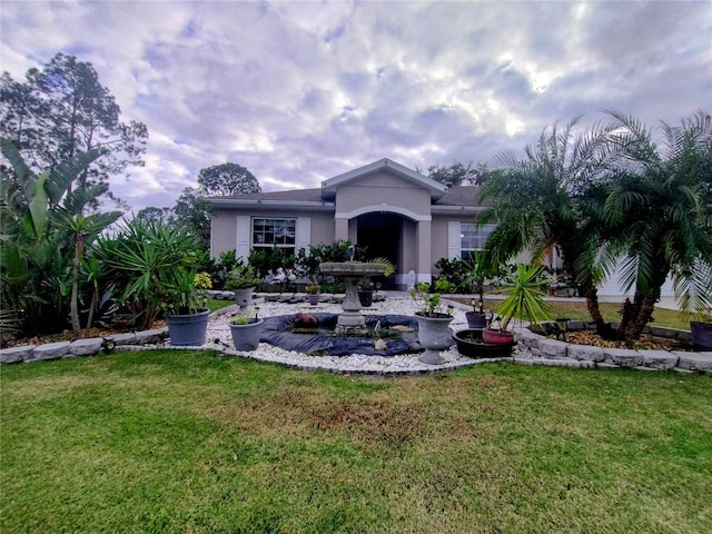 rear view of house featuring stucco siding and a lawn