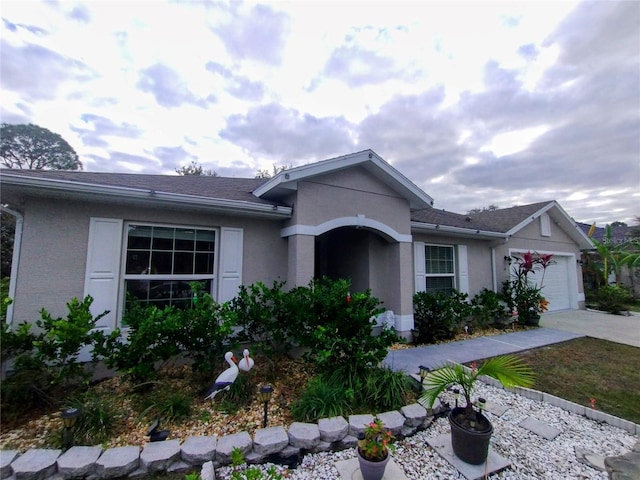 ranch-style home featuring stucco siding, driveway, an attached garage, and a shingled roof