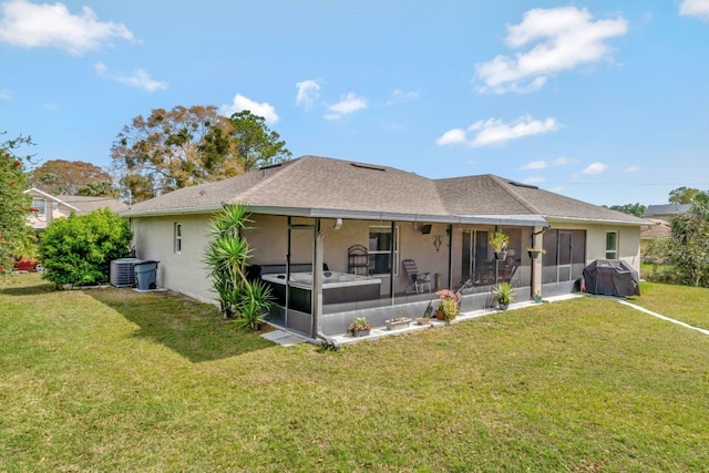 rear view of house with a lawn, a sunroom, central AC, and stucco siding