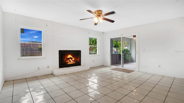 unfurnished living room featuring ceiling fan, light tile patterned floors, and a brick fireplace