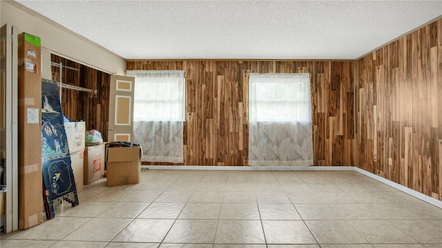 unfurnished room featuring light tile patterned flooring, a textured ceiling, and wood walls