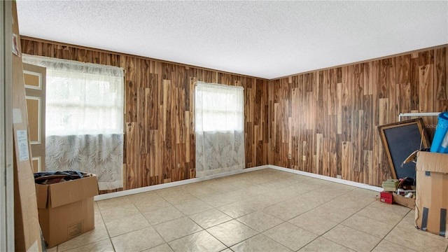 tiled spare room with a textured ceiling and wooden walls