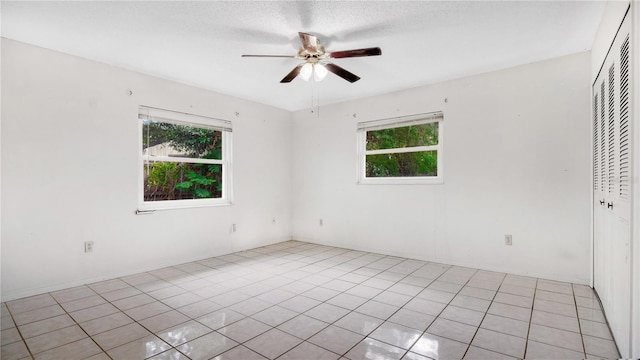 spare room with plenty of natural light, ceiling fan, light tile patterned floors, and a textured ceiling