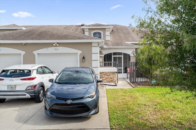 view of front of house featuring a sunroom, a front yard, and a garage