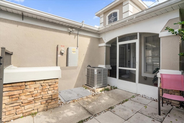 view of patio featuring central air condition unit and a sunroom