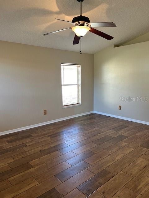 empty room with a textured ceiling, dark hardwood / wood-style flooring, vaulted ceiling, and ceiling fan