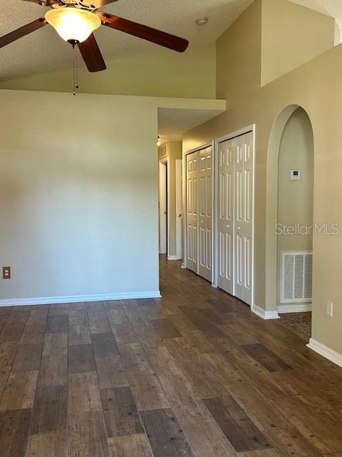 unfurnished room featuring a textured ceiling, dark hardwood / wood-style flooring, ceiling fan, and lofted ceiling