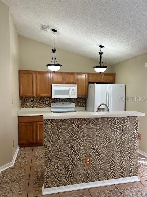 kitchen featuring tile patterned flooring, lofted ceiling, white appliances, and hanging light fixtures