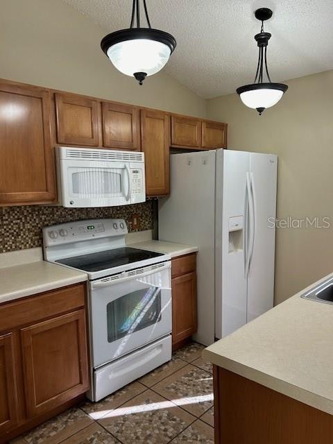 kitchen featuring white appliances, tasteful backsplash, tile patterned floors, and hanging light fixtures