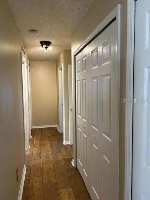 corridor featuring dark hardwood / wood-style floors and a textured ceiling