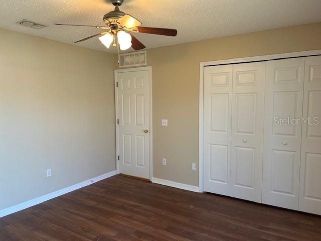 unfurnished bedroom featuring a closet, a textured ceiling, dark hardwood / wood-style floors, and ceiling fan