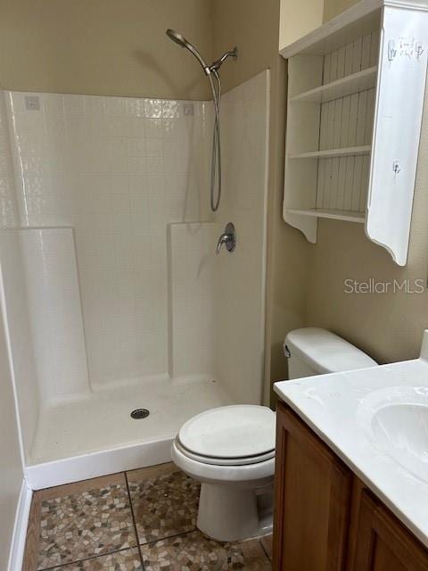 bathroom with a shower, tile patterned floors, vanity, and toilet