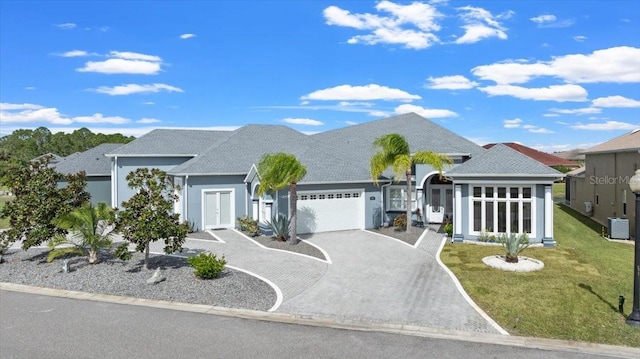 view of front of property with cooling unit, a front yard, and a garage