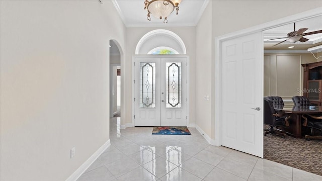 tiled entrance foyer with crown molding, french doors, and ceiling fan