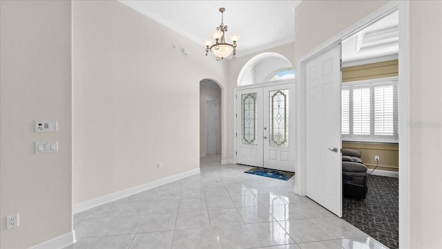 tiled foyer featuring crown molding, french doors, and a chandelier