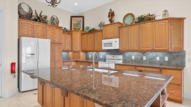 kitchen with crown molding, a center island with sink, light tile patterned flooring, and white appliances