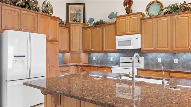 kitchen with white appliances, tasteful backsplash, and dark stone countertops