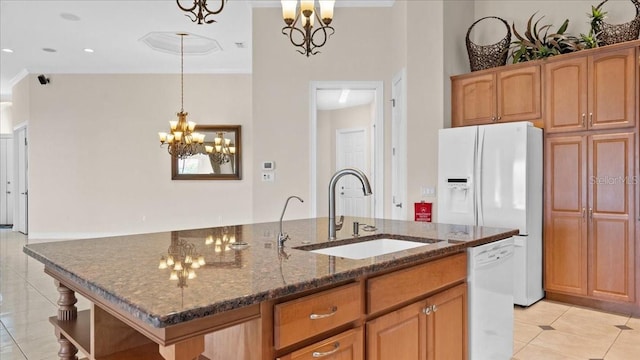 kitchen with pendant lighting, sink, white appliances, and a kitchen island with sink