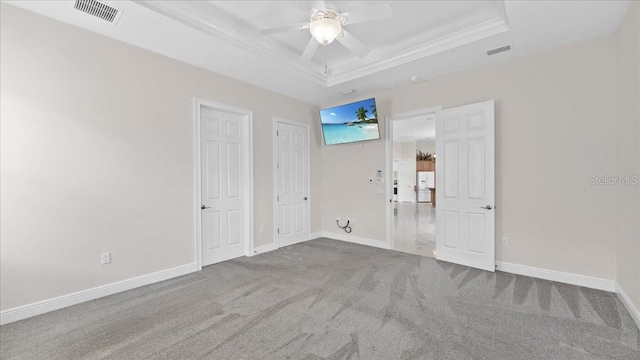 unfurnished bedroom with a tray ceiling, ceiling fan, carpet floors, and white refrigerator