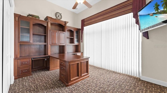 unfurnished office featuring ceiling fan and built in desk