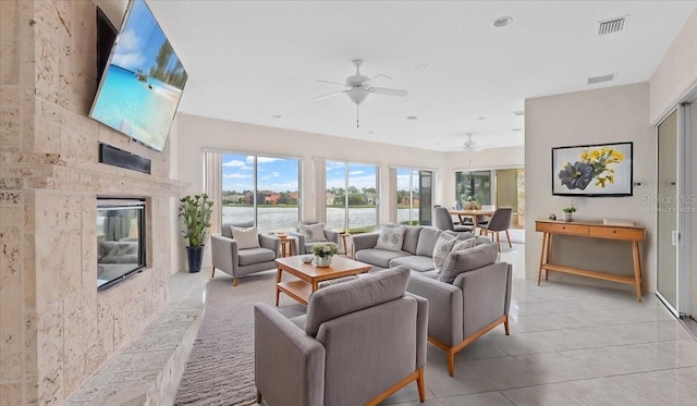 tiled living room featuring ceiling fan and a fireplace