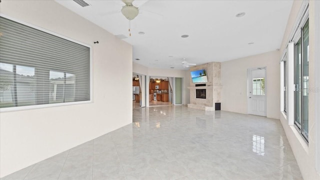 unfurnished living room featuring a premium fireplace and ceiling fan