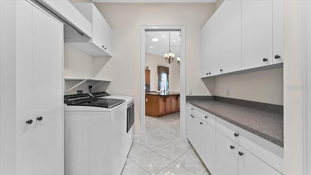 laundry room with cabinets, sink, washer and dryer, light tile patterned floors, and a notable chandelier