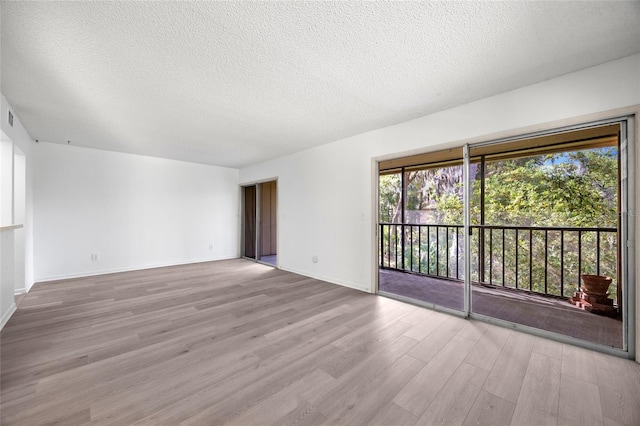 empty room with light wood-type flooring and a textured ceiling