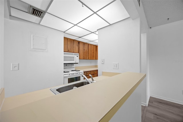 kitchen featuring sink, dark hardwood / wood-style flooring, white appliances, and kitchen peninsula