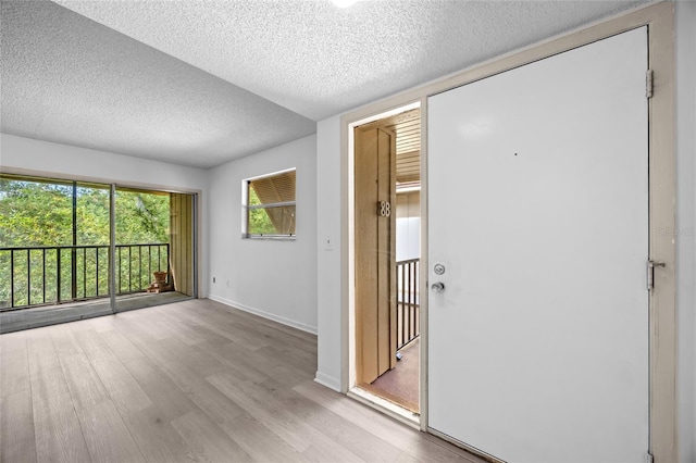 foyer entrance with light hardwood / wood-style floors and a textured ceiling