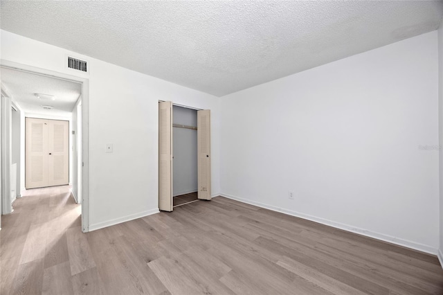 unfurnished bedroom featuring a closet, a textured ceiling, and light wood-type flooring