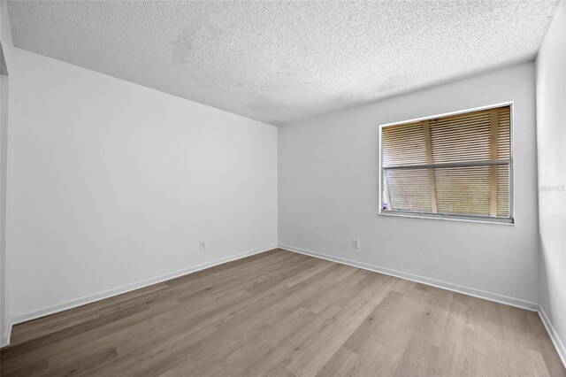 unfurnished room featuring a textured ceiling and light hardwood / wood-style floors