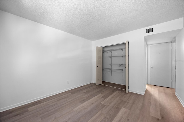 unfurnished bedroom with a textured ceiling, light hardwood / wood-style flooring, and a closet