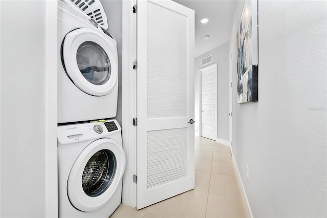 clothes washing area featuring stacked washer / dryer and light tile patterned floors