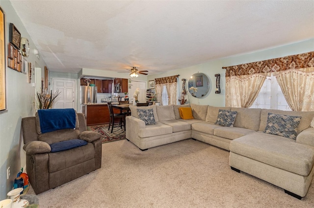 carpeted living room featuring ceiling fan and a textured ceiling