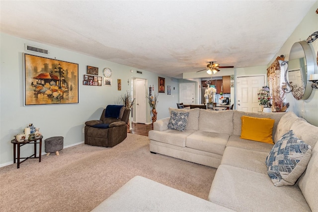 carpeted living room with ceiling fan and a textured ceiling