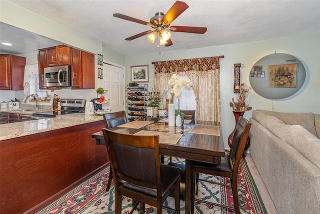 dining space featuring a textured ceiling, ceiling fan, and sink